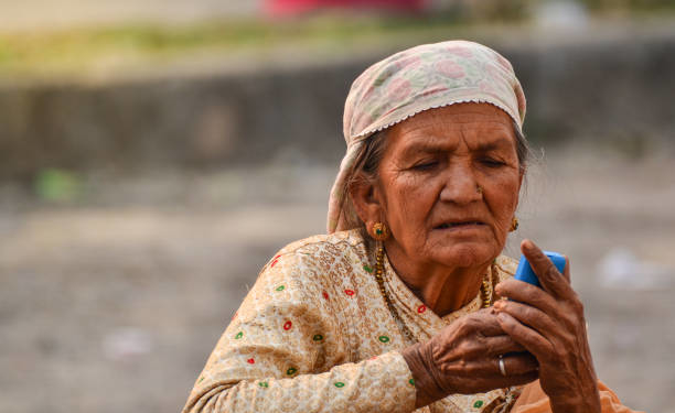 Pokhara, Nepal April-2015, Old women try to checking her blue cell phone at bus station in Nepal